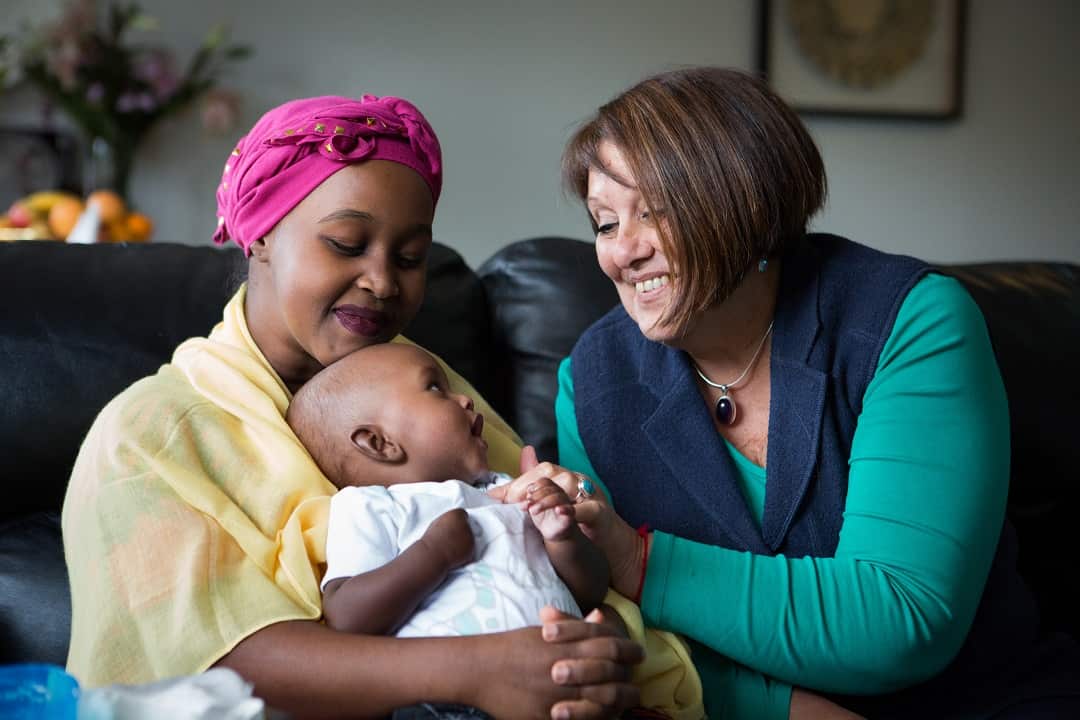 Volunteer doula Elizabeth Mazeyko (right) visits a mother and her new baby.