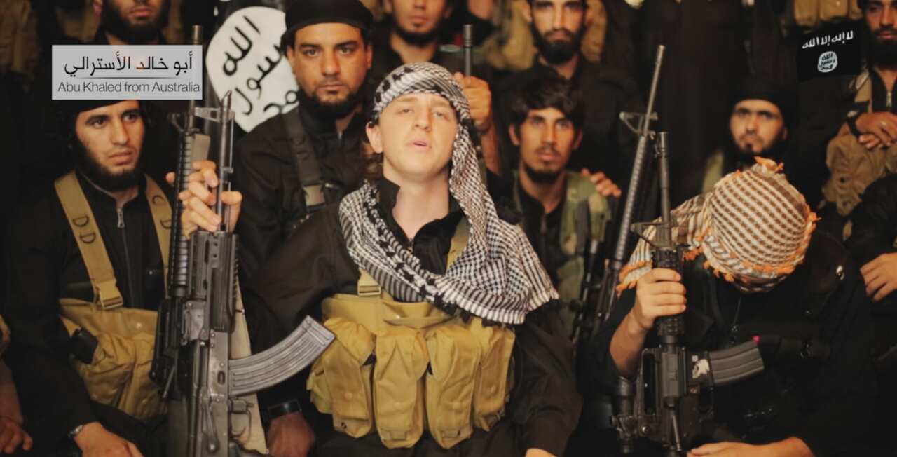 In the video, a man with an Australian accent is shown holding a rifle and wearing military clothing. He is named on the video as Abu Khaled from Australia. (Screenshot)