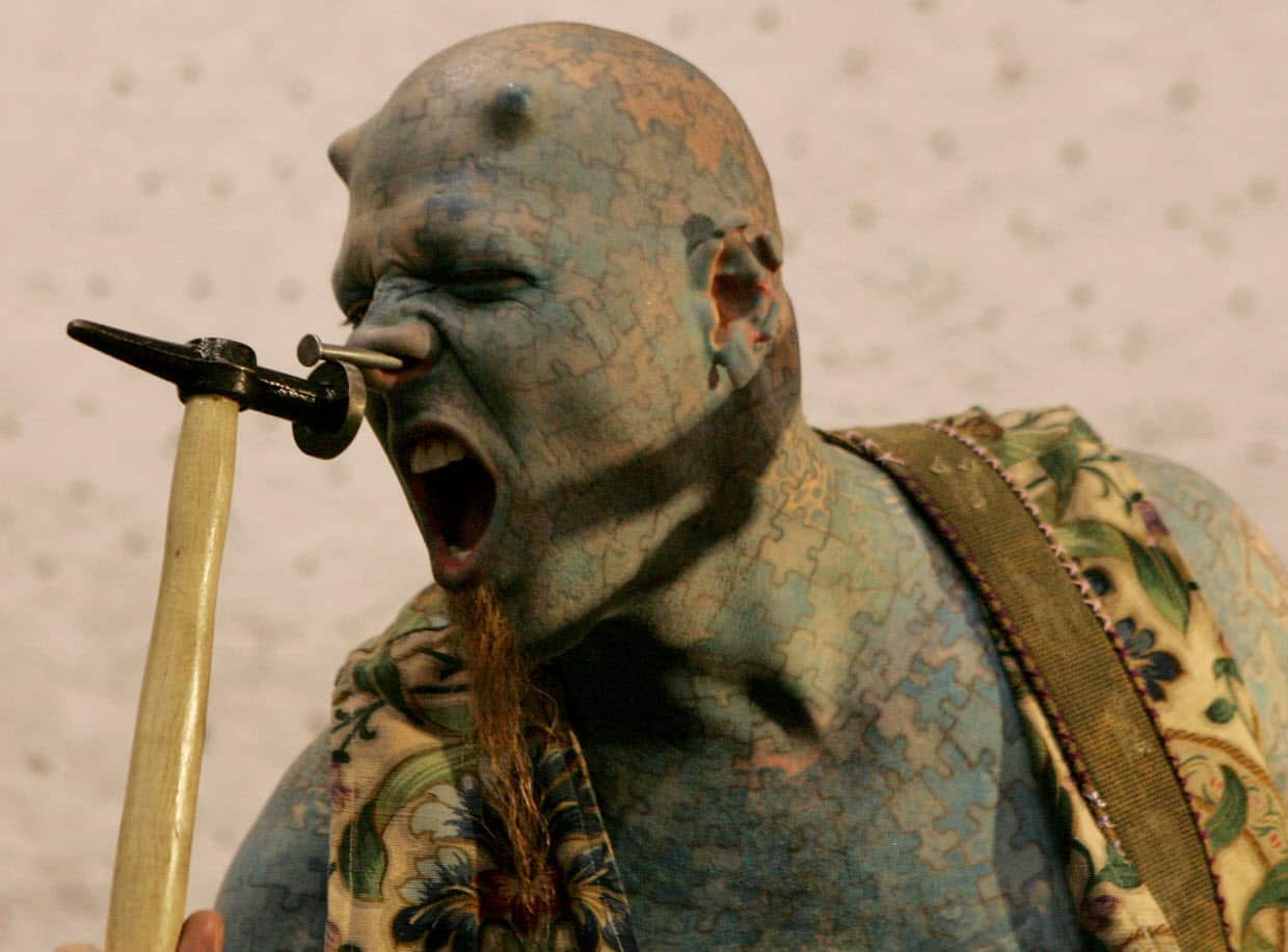 US artist known as "The Enigma" hammers a nail into his nose during an international tattoo convention.