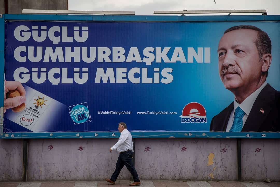 A man walks past a poster of  Turkey's President Recep Tayyip Erdogan.
