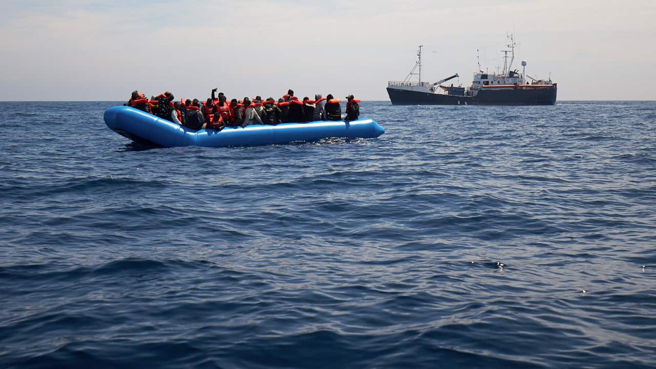 Migrants on a rubber dinghy are approached by the Sea-Watch rescue ship in the waters off Libya.