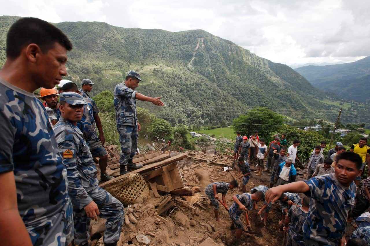 Nepalese policemen search for bodies of victims from the debris after a landslide in Lumle village, about 200 kilometers (125 miles) west of Kathmandu (AAP)