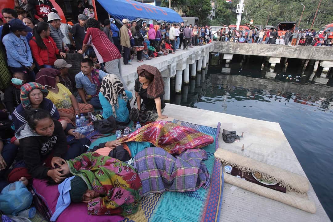 Relatives of victims of a sunken ferry wait for news at the Tigaras port in Toba lake.