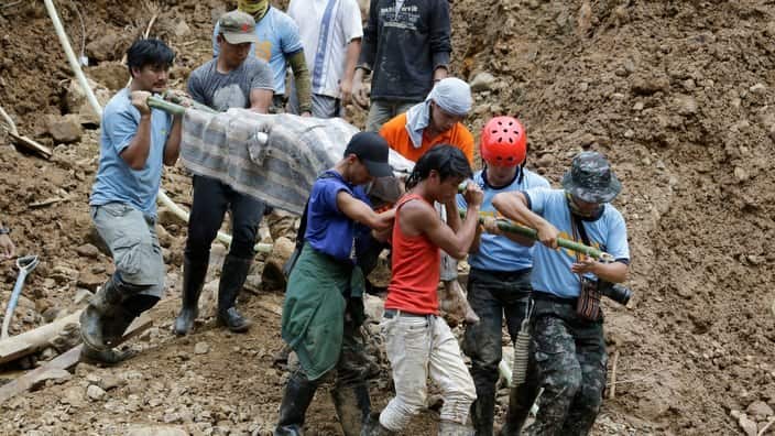 Rescuers carry a body from the site where more victims are have been buried by a landslide after Typhoon Mangkhut lashed northern Philippines.