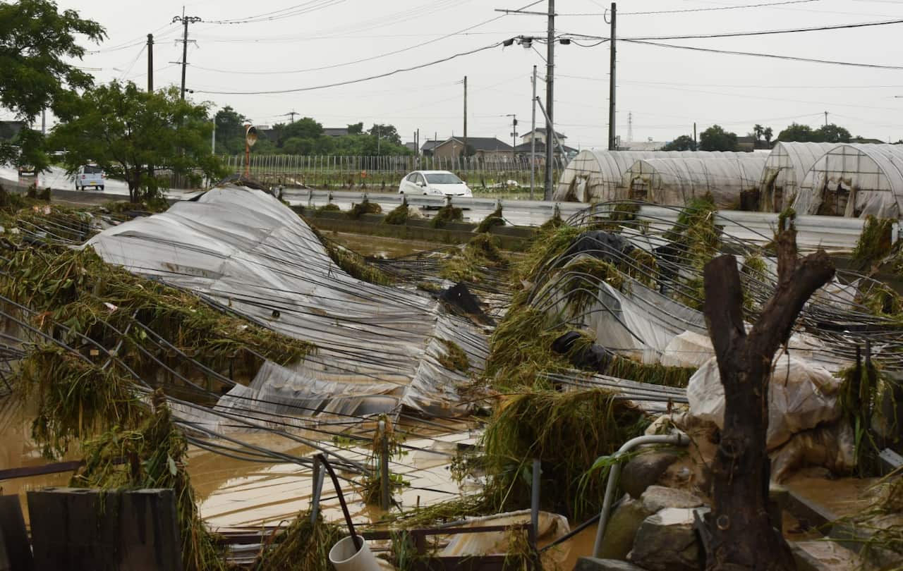 A car drives past damaged agricultural structures following heavy flooding in Asakura, Fukuoka prefecture, on July 6, 2017