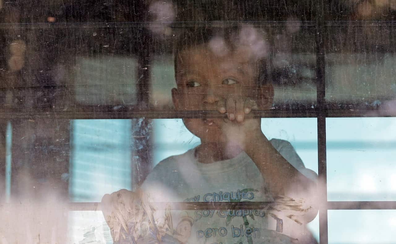 An immigrant child looks out from a U.S. Border Patrol bus leaving as protesters block the street outside the US Border Patrol Central Processing Center