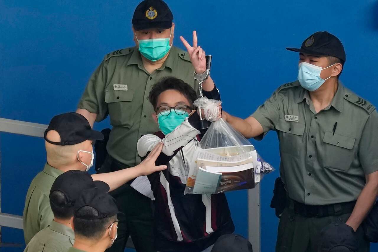 Figo Chan shows a victory sign as he is escorted by Correctional Services officers to a prison van for a court in Hong Kong on 28 May 2021.