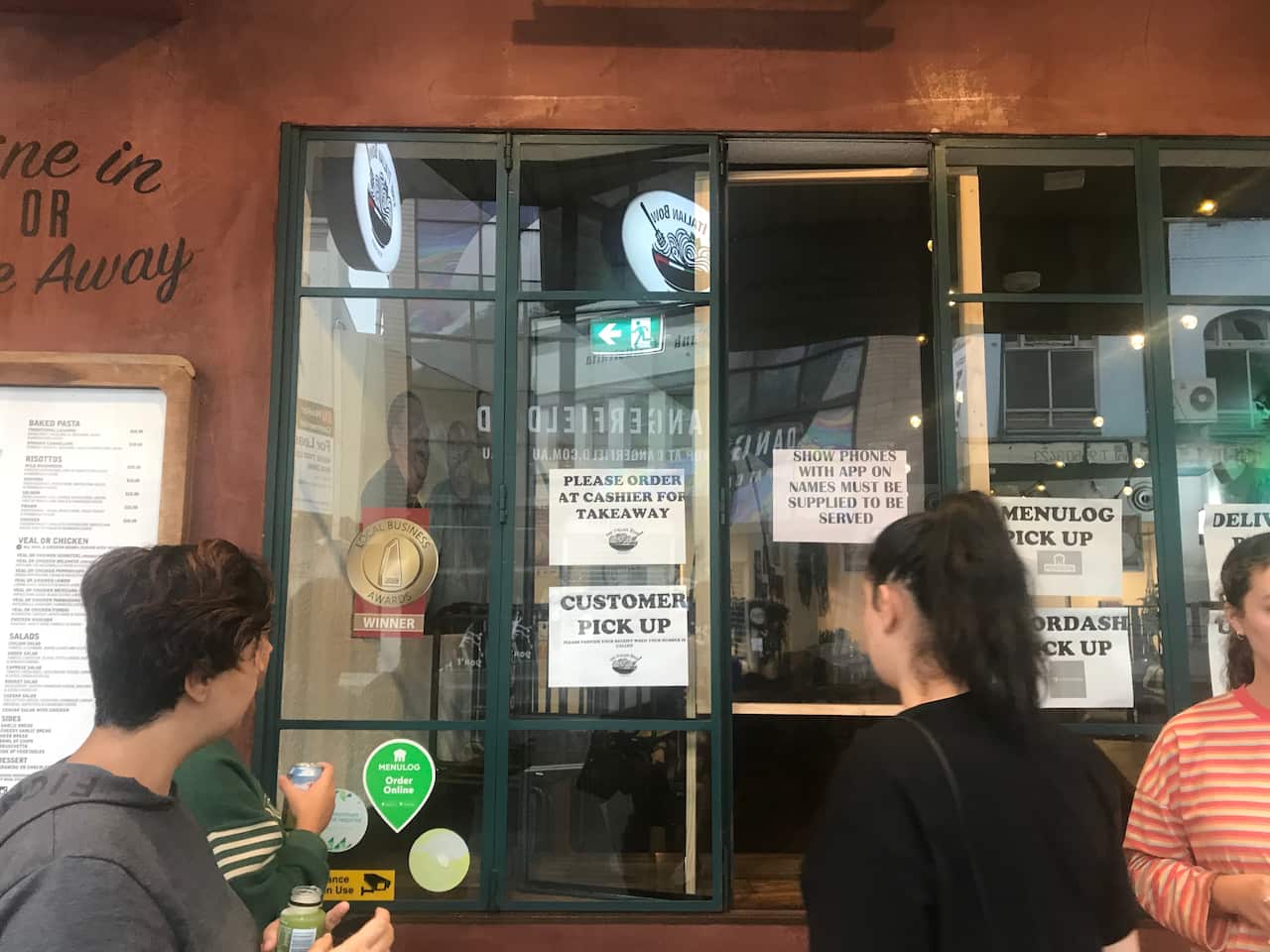 Customers outside the restaurant's makeshift takeaway pick up window. 