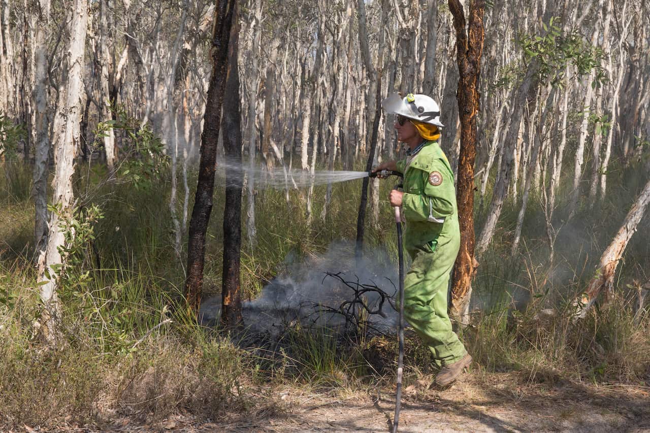 Firefighters extinguish spot fires in the suburb of Noosa North Shore.
