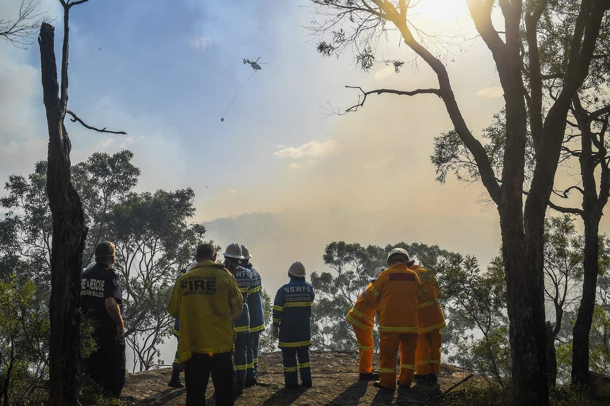 Water bombers are seen fighting a bushfire in Alfords Point as fire crews watch and wait in Sydney on Sunday.
