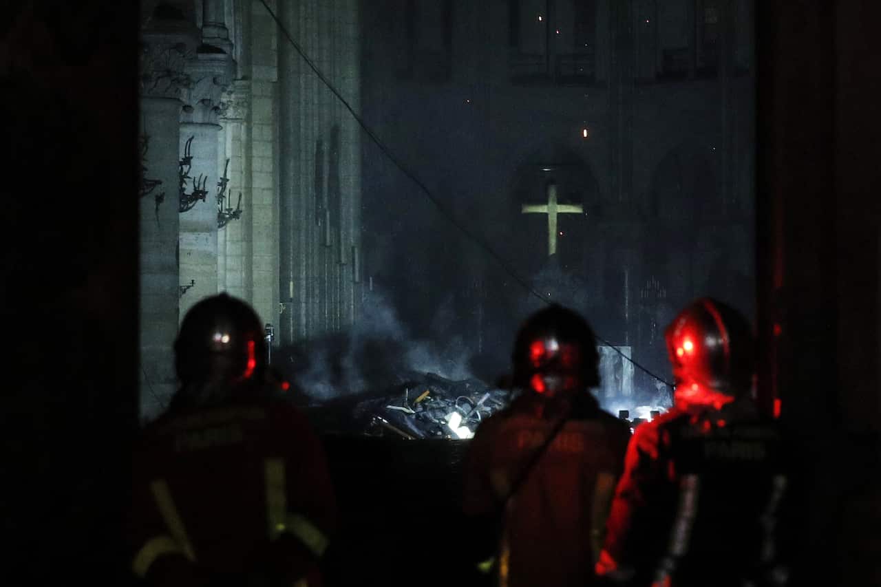 French President Emmanuel Macron (C) looks inside the Notre-Dame Cathedral after the massive fire burnt the roof of the iconic building. 