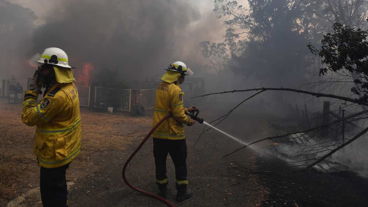 Firefight douse a home lost to a bushfire on Hassall Road in Buxton, New South Wales.