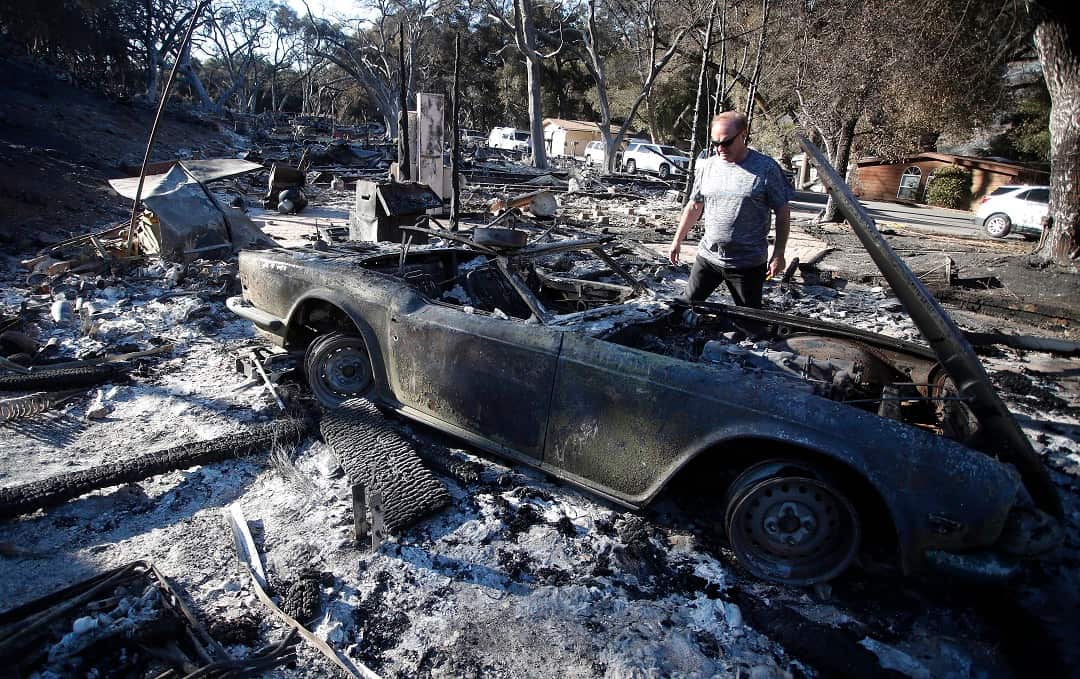 David Spence from the UK looks at a burned out vintage sports destroyed in the fire.