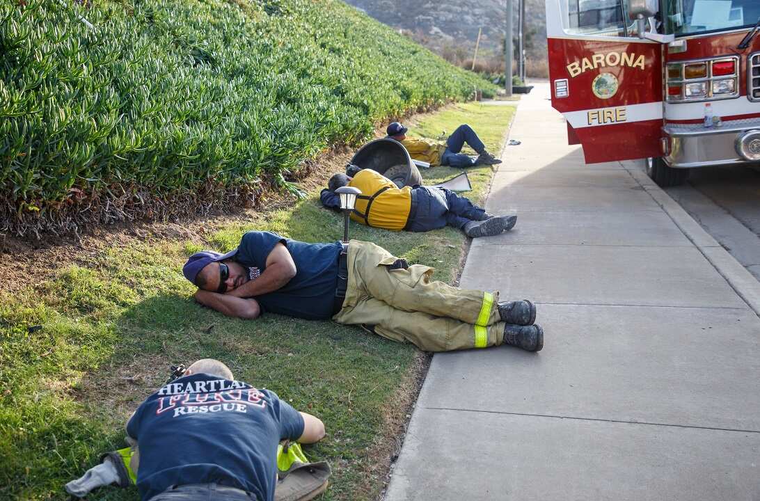 Firefighters take a break after the fire destroyed dozens of trailer homes in the Fallbrook retirement community.
