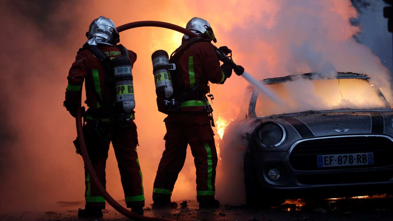 Firefighters try to put out a fire engulfing a car near the Champs-Elysees avenue.