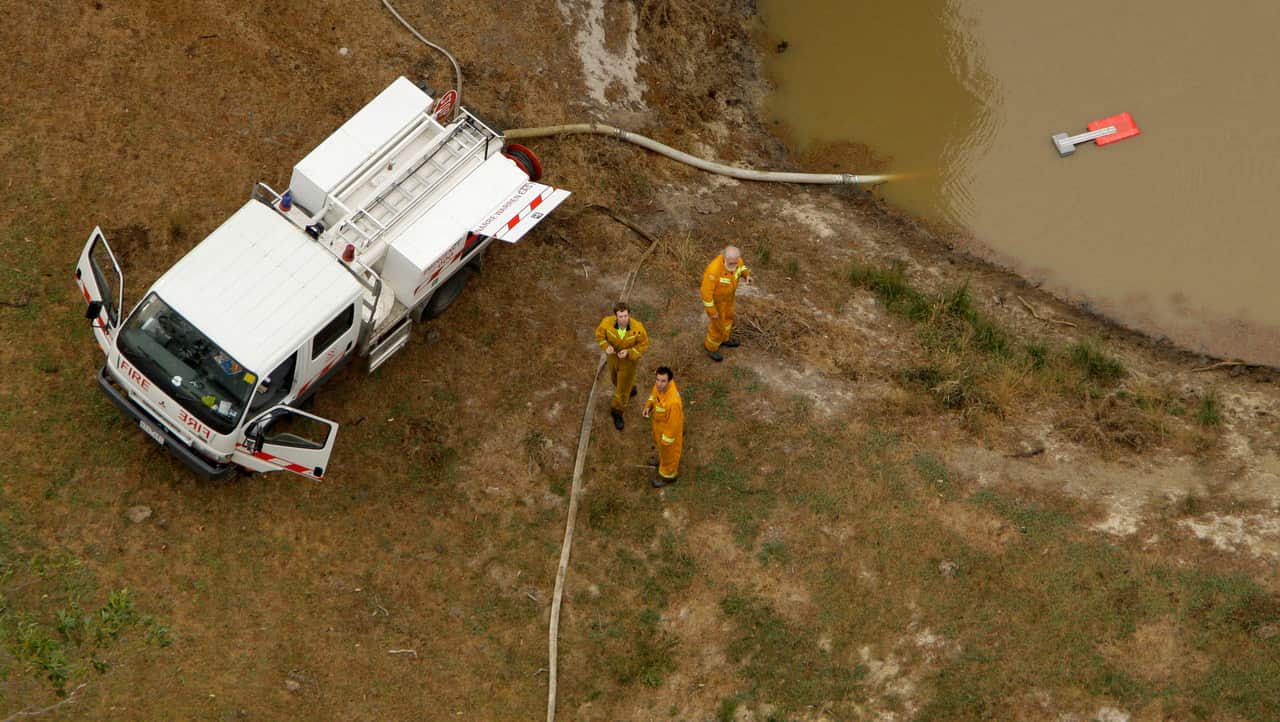 Firefighters fill their truck with water from a dam north east of Melbourne in an attempt to stop the impact of the inferno.