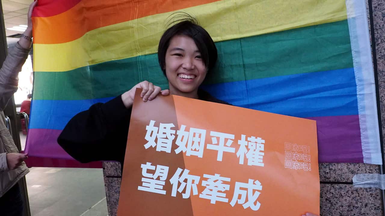 A member of Taiwan's LGBT community poses for a photo with a placard reading 'I Will Go Home to Cast Vote' to urge people to vote for same-sex marriage.