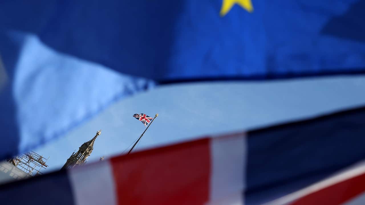 An anti-Brexit protester flies a flag of Europe and a British flag outside British Parliament in London, 24 July 2019. 