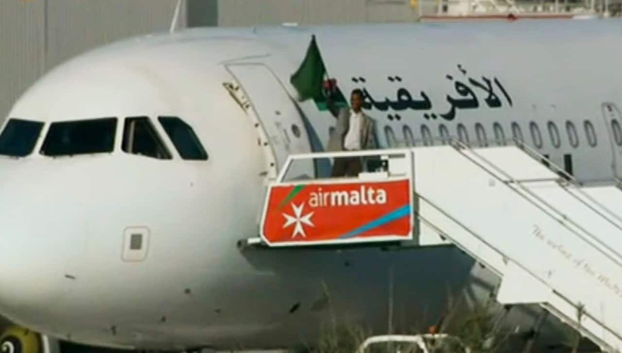 An Afriqiyah Airways plane stands on the tarmac at Malta International airport as an unidentified man waves a flag, Friday, Dec. 23, 2016.