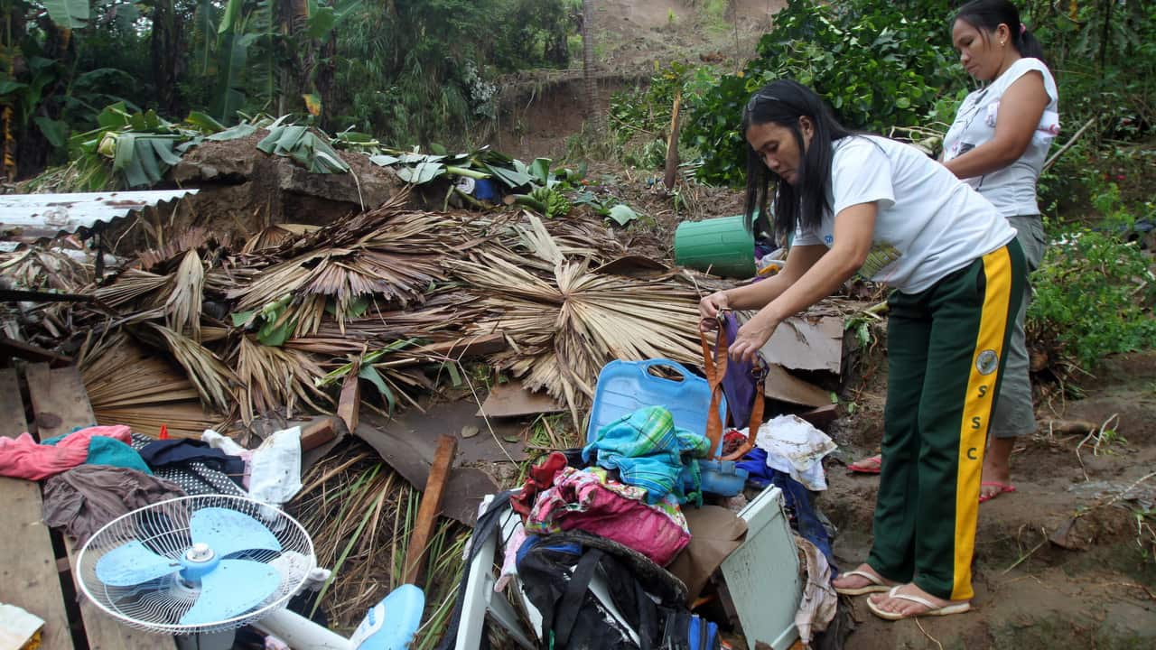 Filipino residents collect belongings from their damaged home at the landslide-hit community in Bulan, Sorsogon province.
