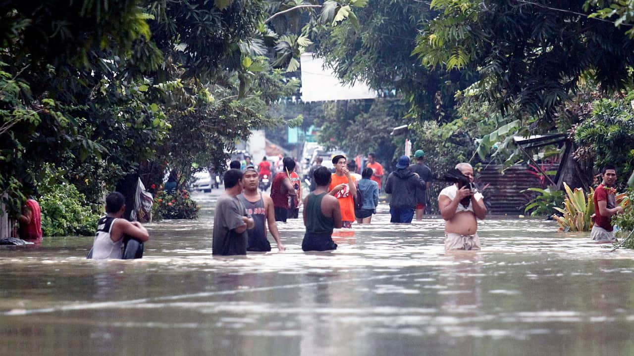Filipino residents wade along a street at a flooded community in the town of Bulan, Sorsogon province.