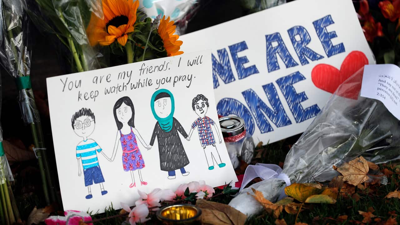 A message card is placed at a collection of flowers left at the Botanical Gardens in Christchurch.
