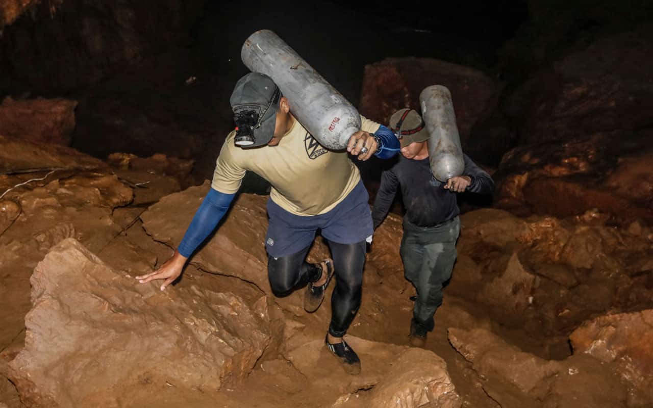Thai rescue personnel carry oxygen tanks inside Tham Luang cave to conduct operations to find the missing members of the children's football team