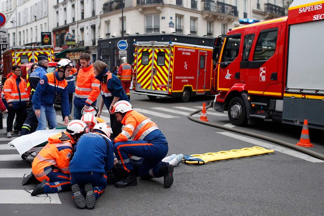 Firefighters tend to a wounded person near the site of a gas leak explosion in Paris.