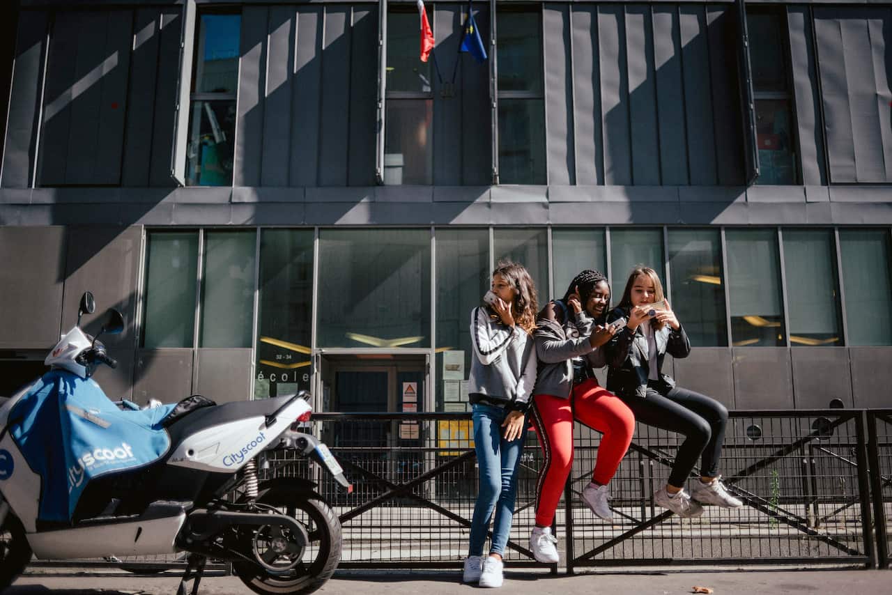 Imane Belaroussi, 13, Grace Blahourou, 13, and Zolinh Masson, 12, use their phones after school in Paris.