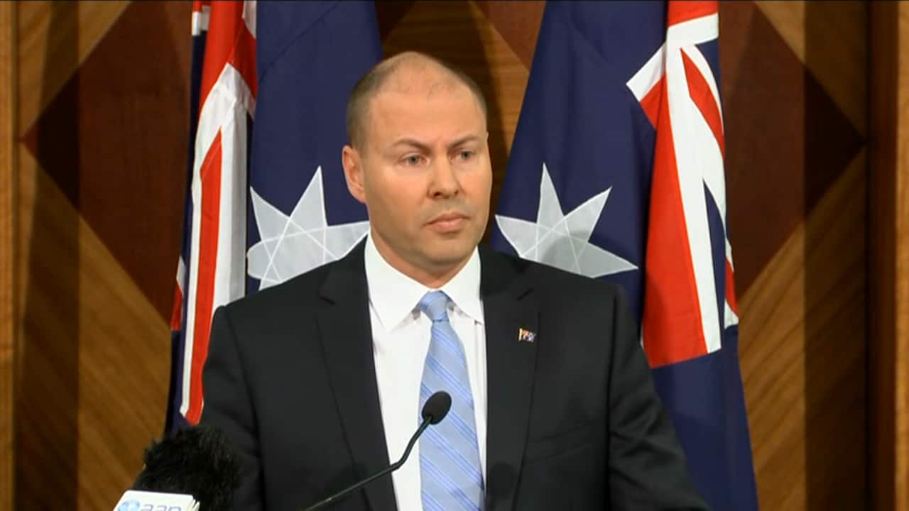 Frydenberg in front of flags