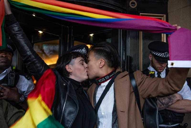 A couple embrace as protesters gather outside the Dorchester Hotel in Park Lane in London.