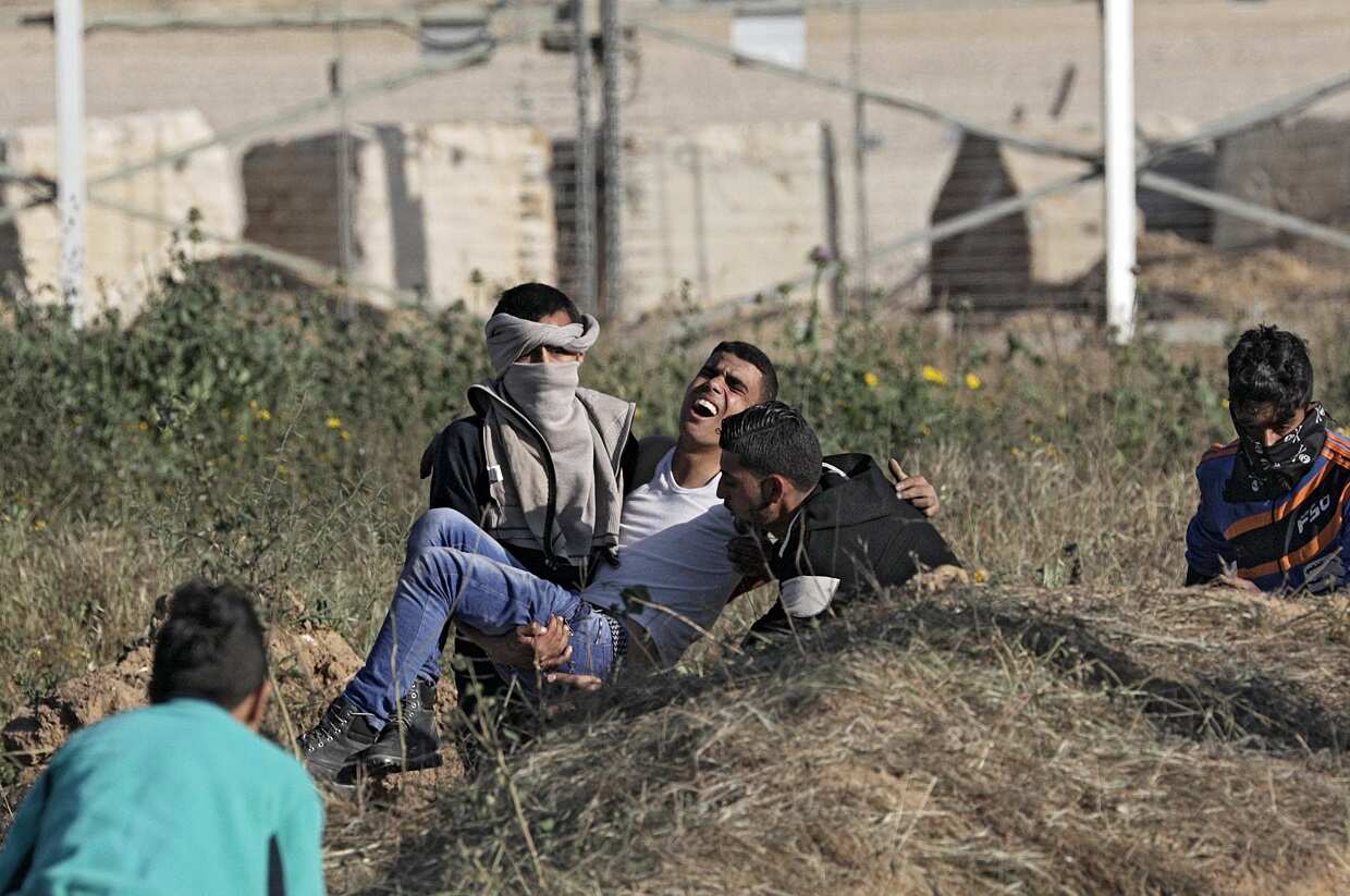 Palestinian protesters carry a wounded youth during clashes with Israeli troops along the border between Israel and Gaza Strip on March 31.
