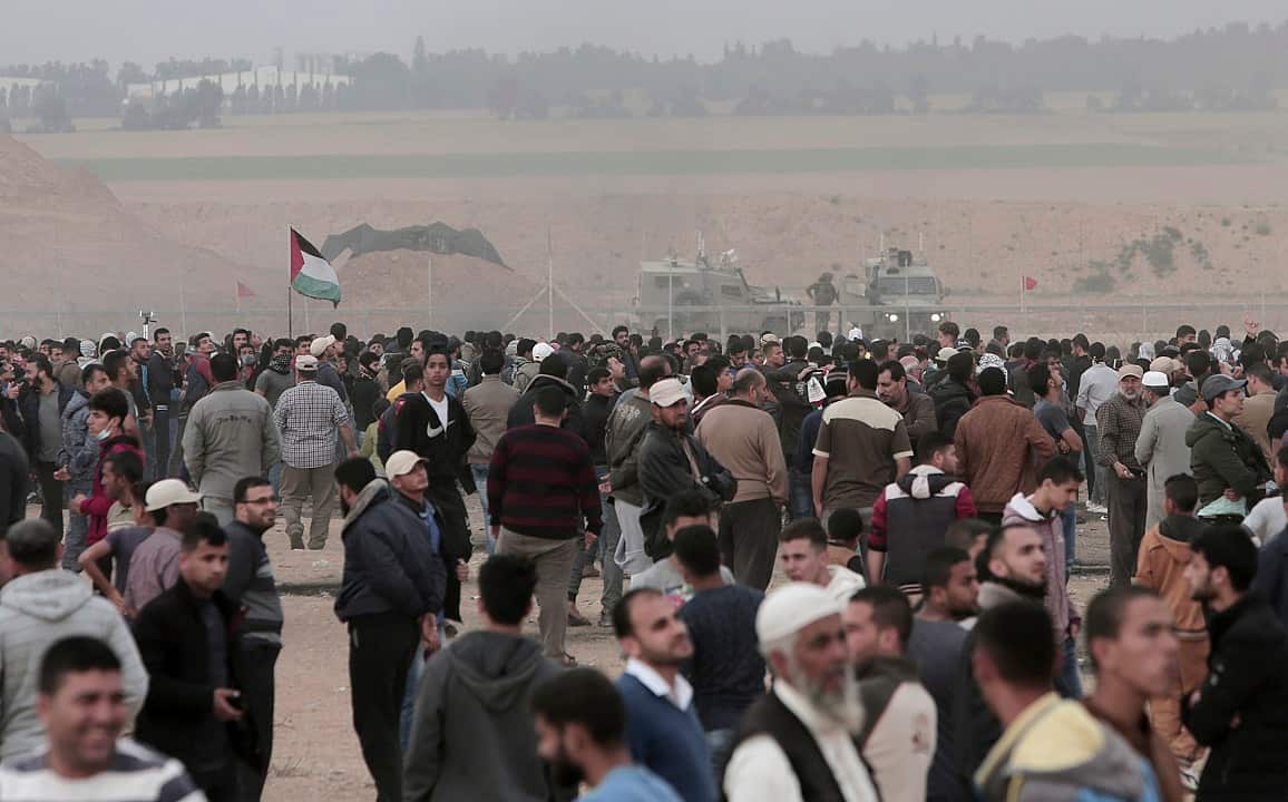 Palestinian protesters gather in front of Israeli jeeps securing the fence during clashes with troops along Gaza's border with Israel.