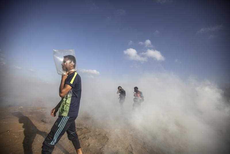 A man uses a plastic bag to protect himself from tear gas as Palestinians and Israeli troops clash.