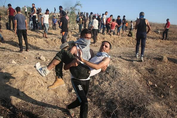 Palestinian protesters flee the border region after Israeli security forces used tear gas.