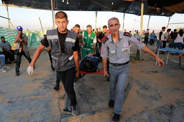 A wounded journalist is taken away to an ambulance after Israeli forces opened fire. Two people were killed in the clashes.