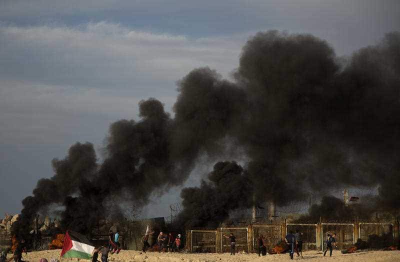 Palestinian protesters burn tires next to the border fence during a protest on the beach at the border with Israel.