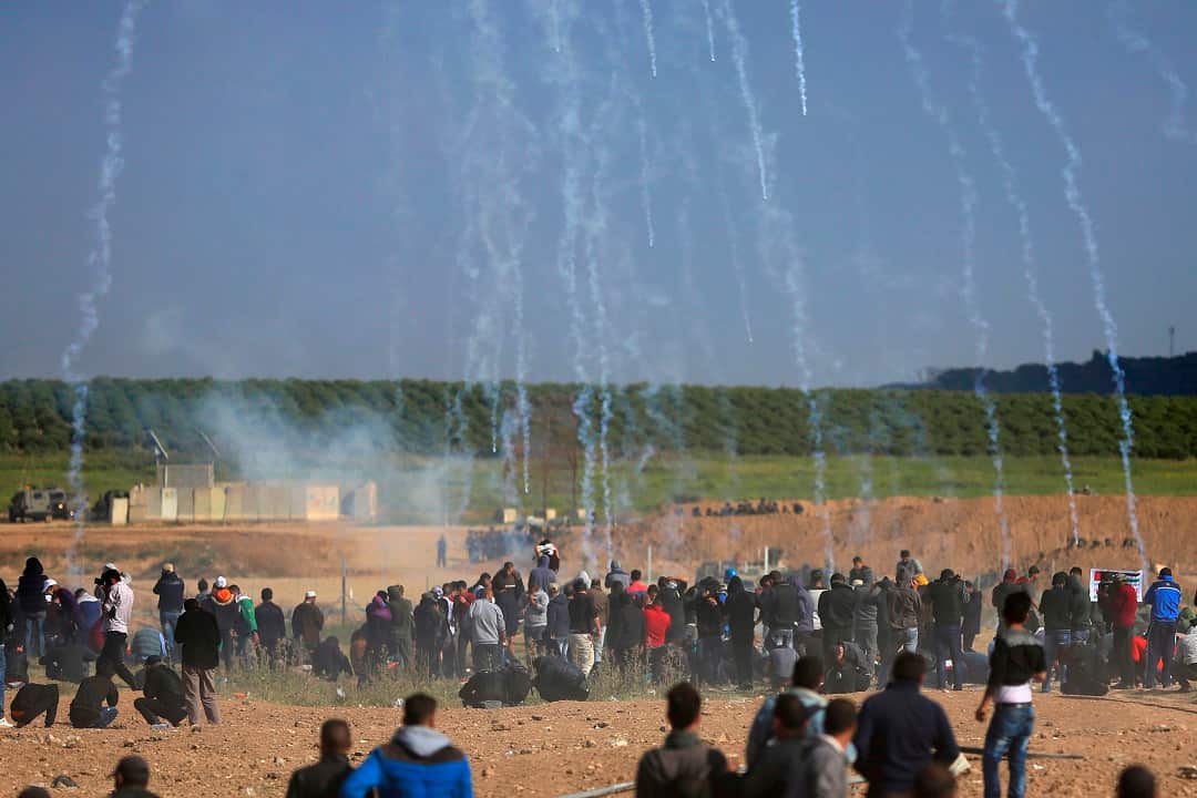 Teargas falls on Palestinian protesters during a demonstration near the Gaza Strip border with Israel