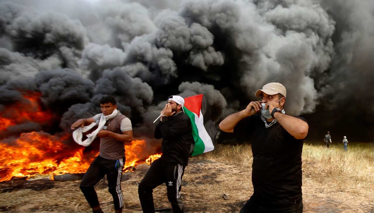 Palestinian protesters chant slogans next to burning tires during clashes with Israeli troops along Gaza's border with Israel