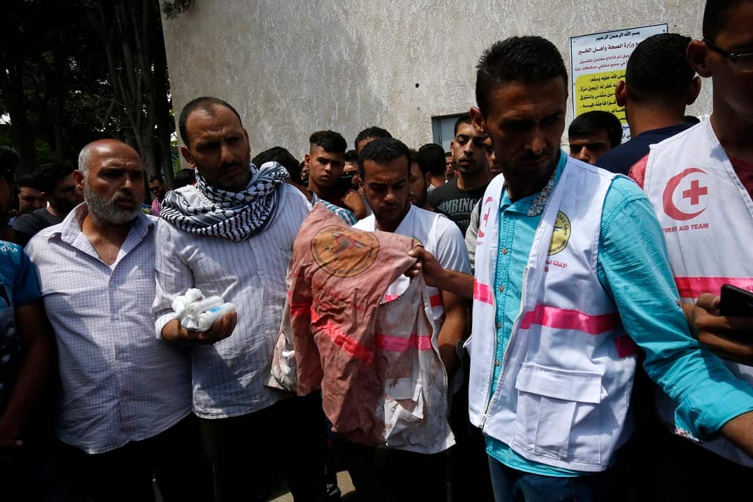 Father Razan al-Najjar holds her jacket covered with blood during her funeral.