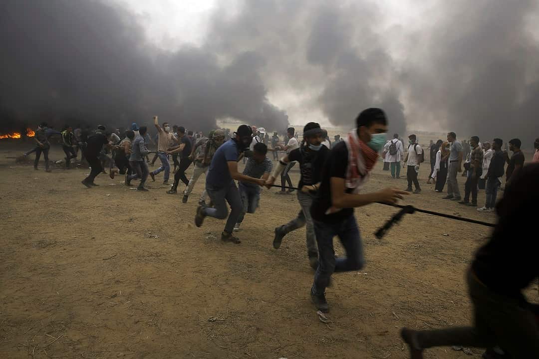 Palestinian protesters try to pull down the fence of the border after they burn tires during a protest at Gaza's border with Israel. 