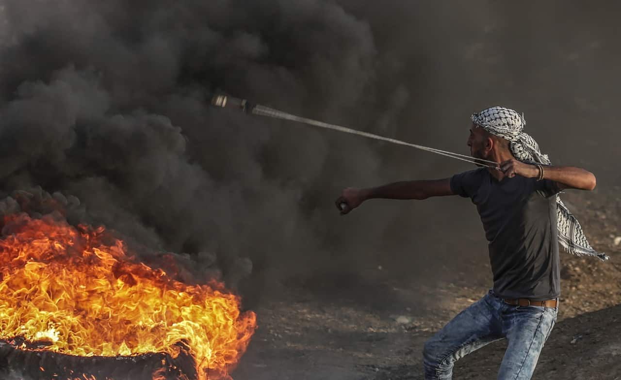 A Palestinian protester throw stones during the clashes near the border between Israel and Gaza Strip, eastern Gaza City on, 18 May 2018. 