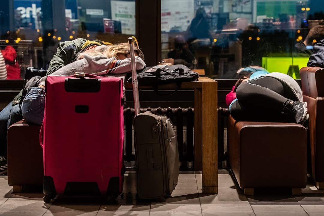 Travellers rest on their luggage as they wait at Schoenefeld airport in Berlin.