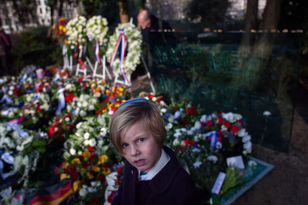 A boy, wearing a Jewish skullcap, or kippa, walks away after putting a stone on the "Auschwitz Never Again" monument.