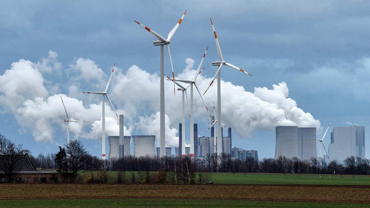 Renewable and fossil-fuel energy is produced with wind generators seen in front of a coal fired power plant near Jackerath, Germany.
