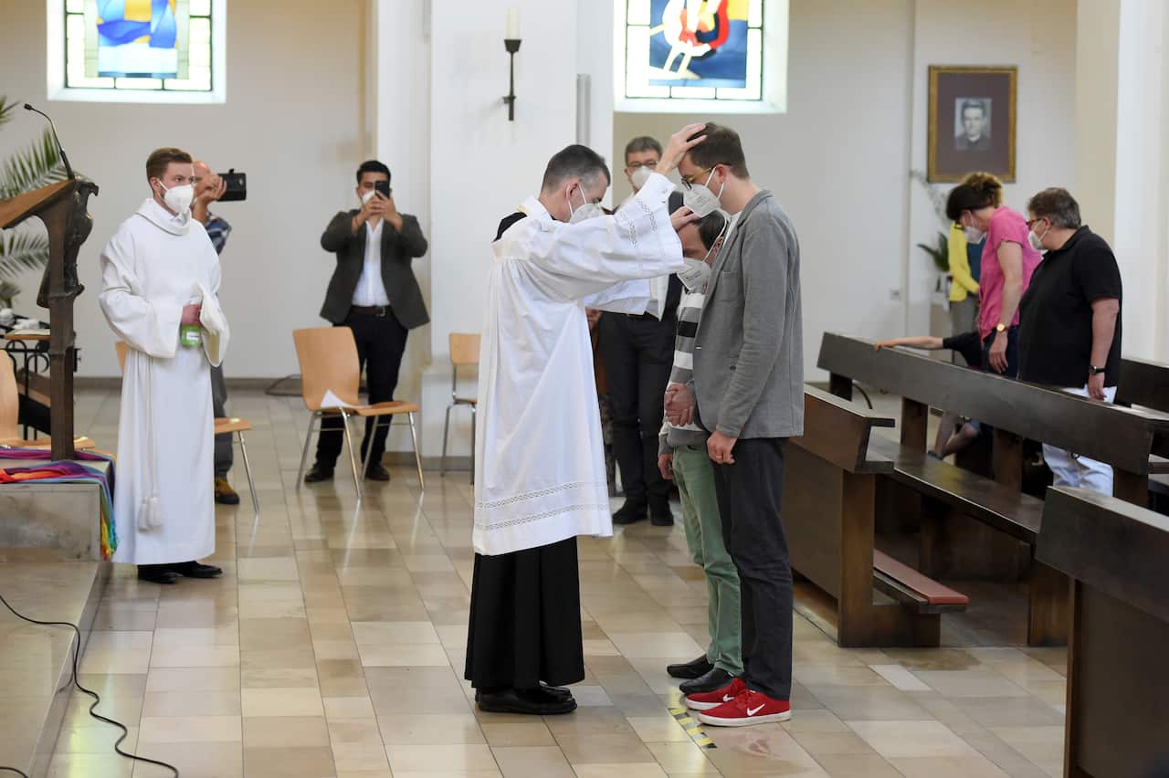 Vicar Wolfgang Rothe, center, blesses two men during a Catholic service with the blessing of same-sex couples in St Benedict's Church in Munich on Sunday.