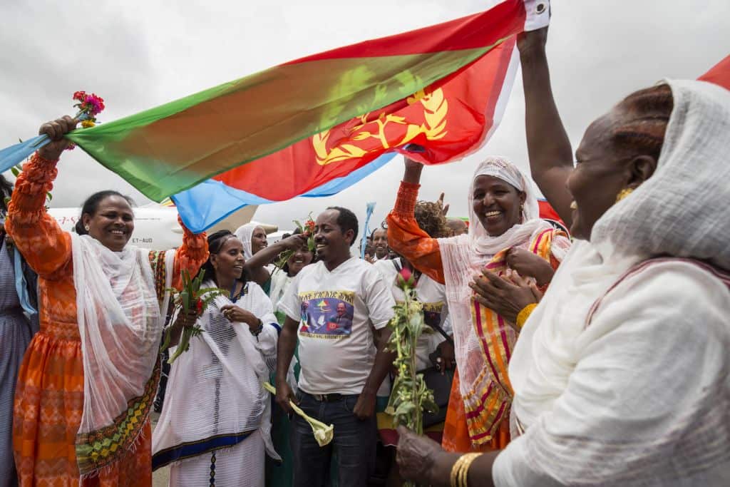 Eritrean women hold up the flag of Eritrea on July 18, 2018, to welcome passengers of the flight from Ethiopian capital Addis Ababa, upon their arrival at the Asmara International airport.