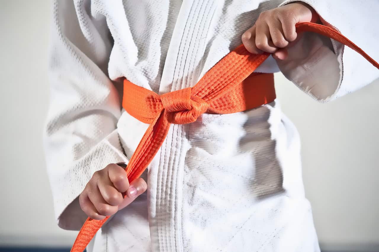 African American boy tightening karate belt