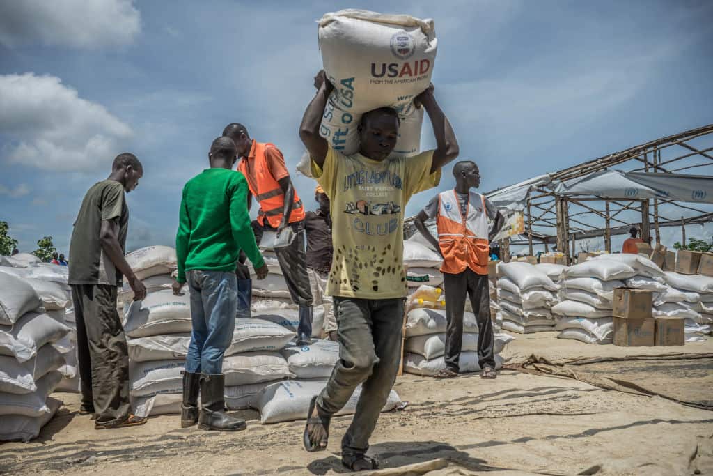 A South Sudanese refugee seen carrying a pack of 50 KG of