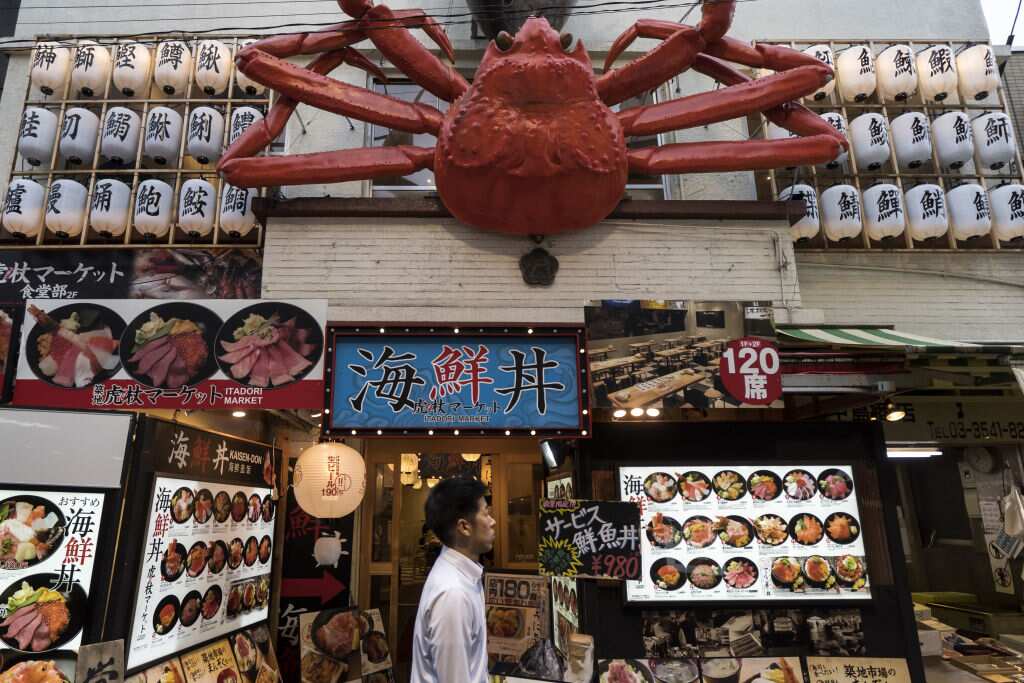 A man walks past a seafood restaurant at Tsukiji Outer Market in Tokyo, Japan.